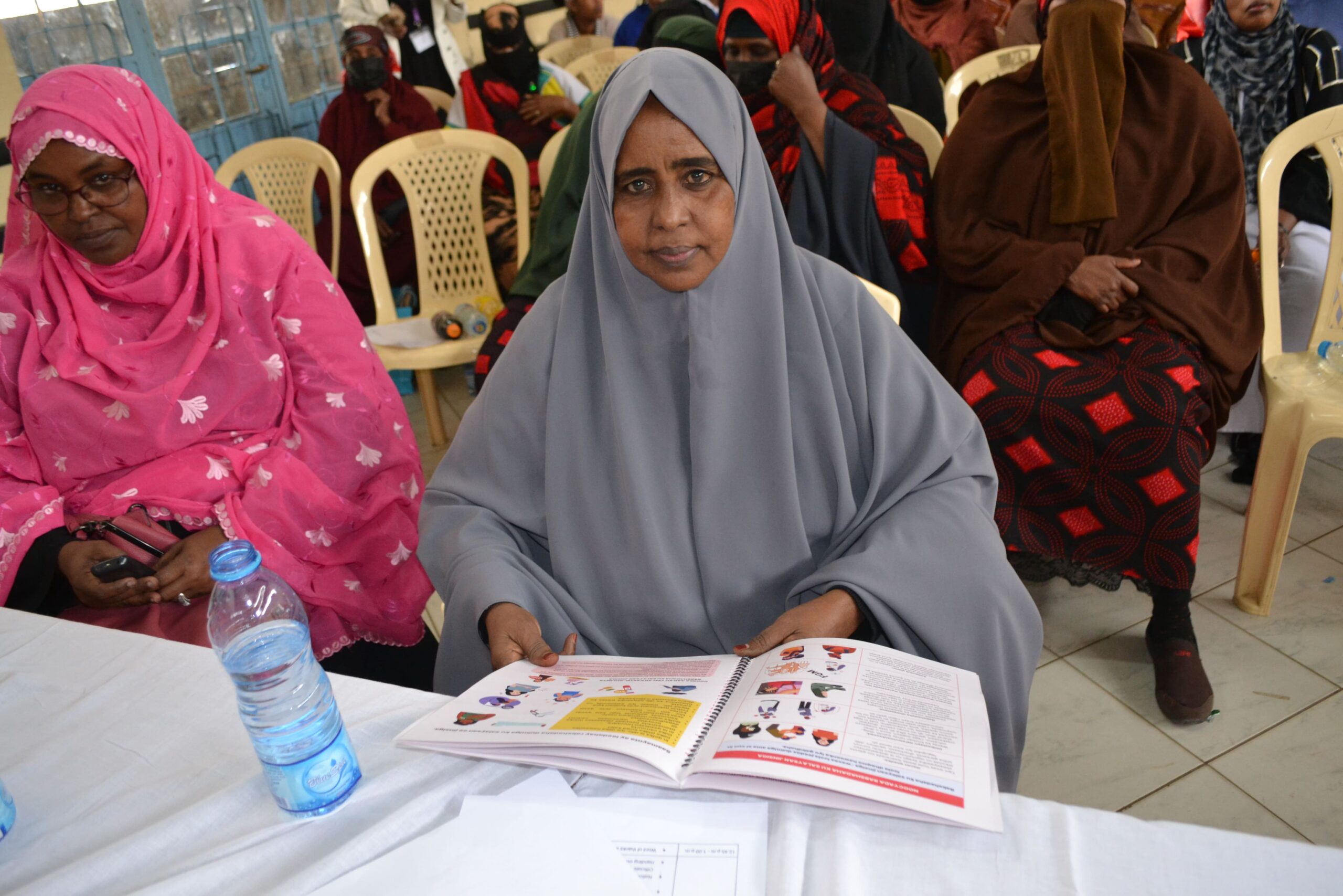 Somali woman holding book from the Kueleka Mabadiliko program